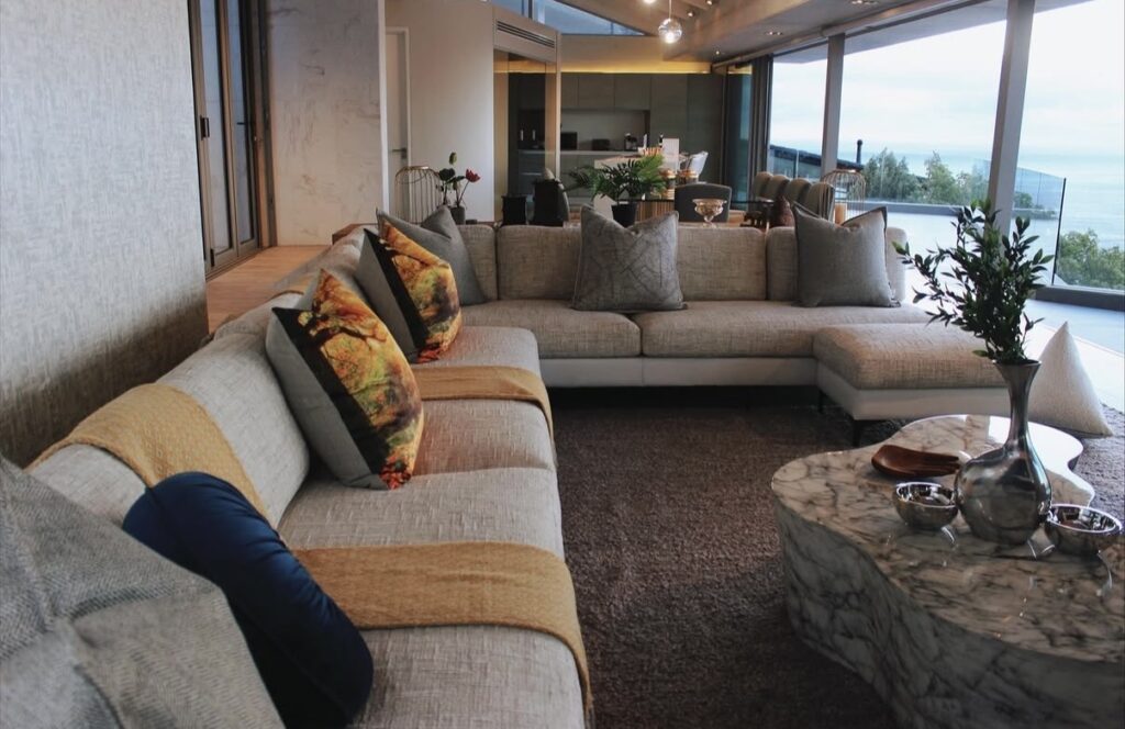 Beige sectional sofa with patterned pillows overlooking a lake view