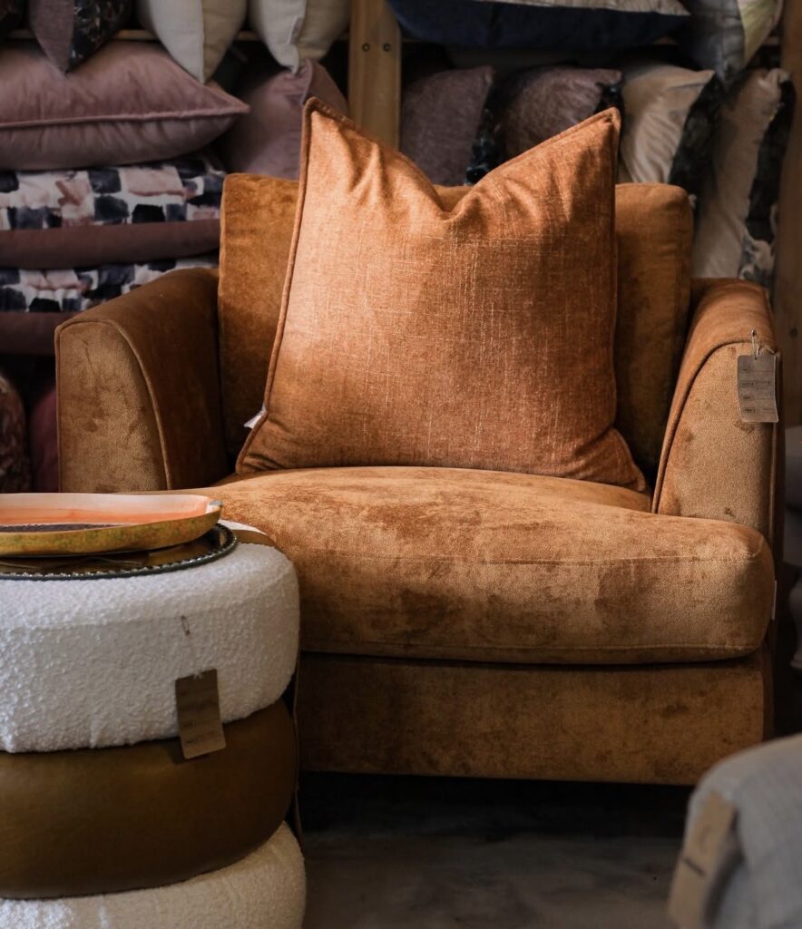 Brown chair paired with a white ottoman and pillows
