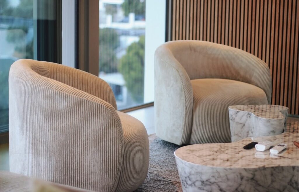 Curved modern armchairs in cream corduroy beside a marble table